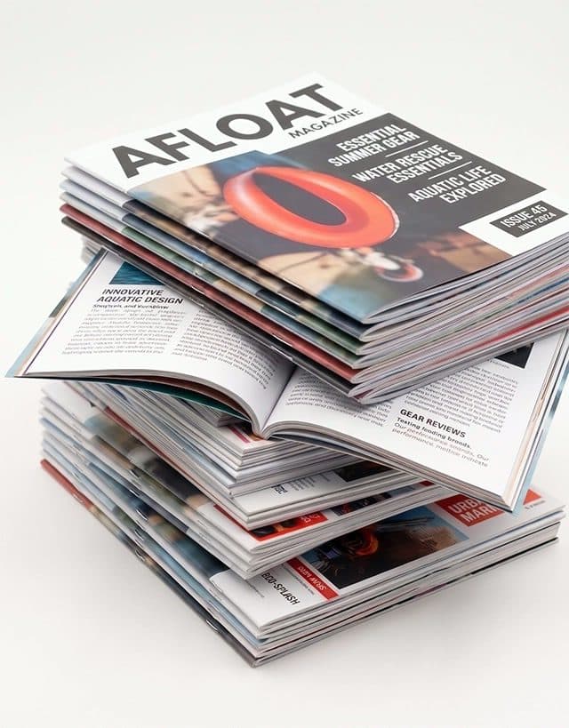 Stack of printed booklets with a bridge blueprint cover design, fanned out on concrete.